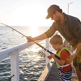 Man fishing with his son at pier