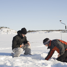 Two people ice fishing in the snow