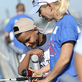 Woman teaching kid how to fish