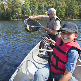 Child and grandfather fishing from boat