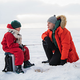 Dad teaching his son how to go ice fishing