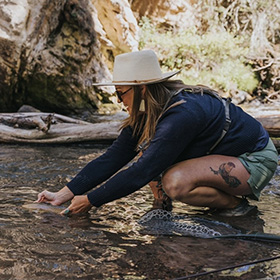 Woman fly fishing releasing fish onto water