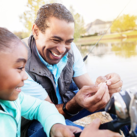 Man teaching granddaughter how to hook bait