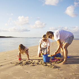 two moms on the beach with their daughter