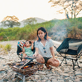 mother and son grilling fish outdoors 