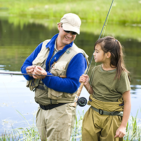 Man teaching girl how to fly fish