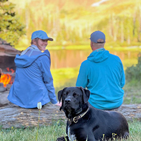 Couple sitting by the water with their dog
